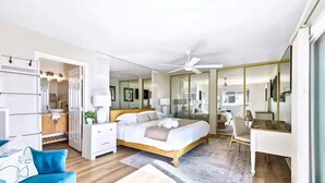 Quarto moderno com cama, escrivaninha e cadeira. Há um guarda-roupa e um espelho.