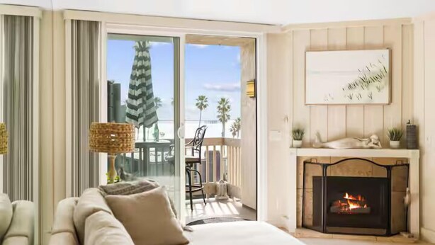 Uma sala de estar com sofá, lareira e vista para o exterior.