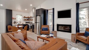 Een moderne woonkamer met een bruine leren bank, een bijzettafeltje en een open haard.
