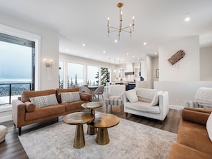 Ein geräumiger Wohnbereich mit einem braunen Sofa, weißen Sessel und einem Esstisch.