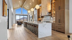 A spacious kitchen with a large island, wooden cabinets, and a view of a mountainous landscape. - 2 Min to Jordanelle Gondola Hot Tub Spa Suite Movie Room & Mountain Views Skyridge Summit by Avantstay (Heber City)