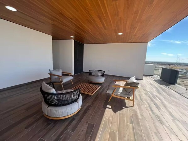 A modern outdoor seating area with a wooden ceiling and a view of the landscape.