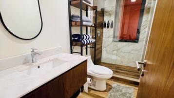 A modern bathroom with a wooden vanity, a toilet, and a glass shower enclosure.