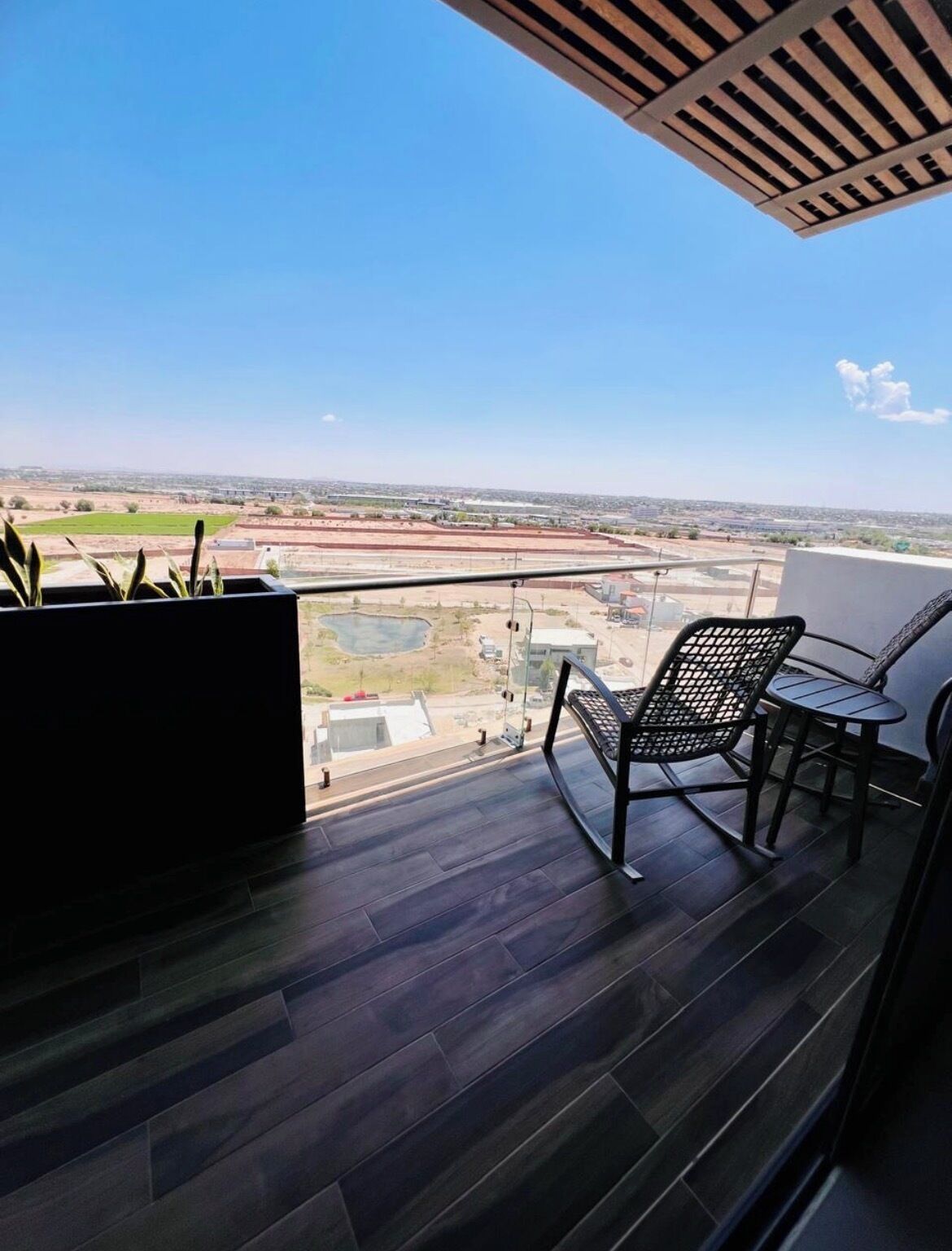 A balcony with a view of a distant landscape, a chair, and a small table.