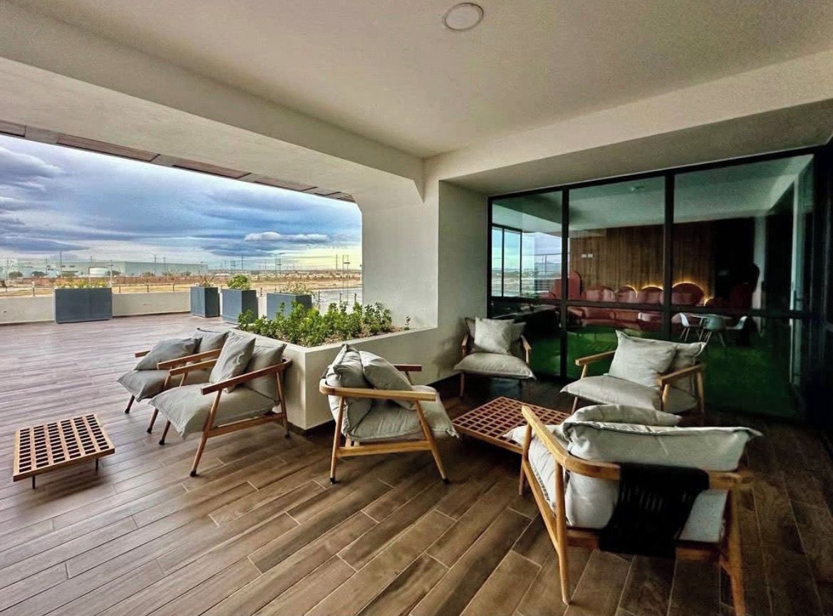 A spacious balcony with wooden flooring, multiple seating areas with cushions, and a view of the cityscape.
