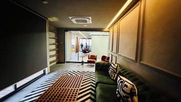 Een modern interieur met een groene bank, een rug met patroon en een zithoek met stoelen.