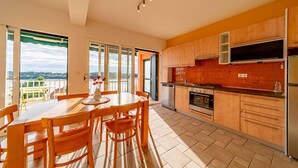 Une cuisine moderne avec des meubles en bois, un coin repas avec une table et des chaises, et une vue sur l’extérieur.