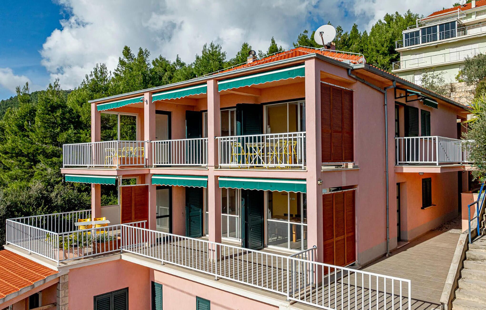 Un immeuble à plusieurs étages, doté de balcons, d’une antenne parabolique et d’un escalier menant à l’entrée.