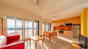 Un appartement moderne doté d’un balcon, d’un coin repas, d’une cuisine et d’un salon avec un canapé rouge.