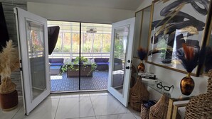 Un interior moderno con un ventanal de vidrio que da a un balcón con sofá azul y plantas.