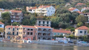 Una cittadina costiera con edifici lungo il lungomare, tra cui un edificio a più piani con un cortile centrale.