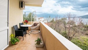 Ein Balkon mit Tisch, zwei Stühlen, einer Hängematte und Topfpflanzen.