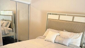 Un dormitorio moderno con cama, armario y espejo.