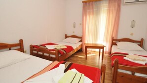 Une chambre d’hôtel avec deux lits simples, une table en bois et une fenêtre avec des rideaux.