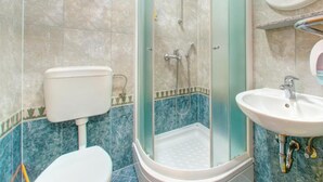 Une salle de bain avec une douche à parois de verre, des toilettes et un lavabo.