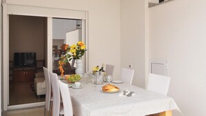 Un comedor con una mesa dispuesta para dos, un jarrón con flores, una botella de champán y un frutero.
