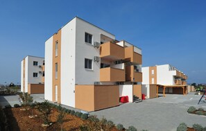 A modern multi-story residential building with balconies, a covered outdoor seating area, and a landscaped garden. - Nice apartment in Nin with WiFi (Nin)