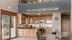 A modern kitchen with wooden cabinets, a dining area with a table and chairs, and a large sliding glass door leading to an outdoor space. - Villa Phoebeia, Wonderful Sea Views, Outdoor Infinity Pool, Antipata, Kefalonia (Kefalonia)