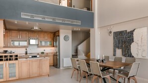 A modern kitchen with wooden cabinets, a built-in microwave, and a dining area with wicker chairs and a wooden table. - Villa Phoebeia, Wonderful Sea Views, Outdoor Infinity Pool, Antipata, Kefalonia (Kefalonia)