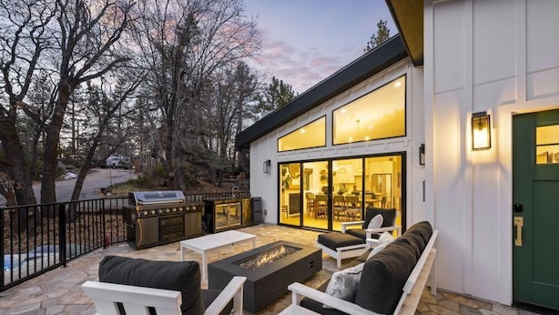 Un patio exterior con un brasero, asientos y una zona de parrilla.