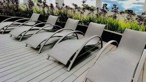 A row of grey wicker lounge chairs on a wooden deck with a view of plants and a cloudy sky. - Stylish & Cozy Studio Retreat in Iloilo City (Iloilo City)