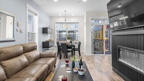 A modern living room with a leather sofa, dining table, and chairs, a fireplace, and a view of the outside. - Rooftop Deck w/ Hot Tub Near Dining & Ski Slopes The Lookout by Avantstay (Park City)