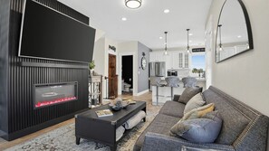 A modern living room with a fireplace, a sofa, a coffee table, and a kitchen in the background. - Rooftop Deck w/ Hot Tub Near Dining & Ski Slopes The Lookout by Avantstay (Park City)