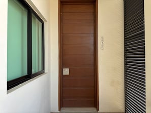 A brown door with a window to the left and a shutter to the right. - Rio Nilo Apartments (Mazatlán)
