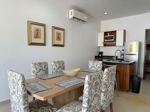 Een eetruimte met een houten tafel, gestreepte stoelen en kunstwerken in lijsten aan de muur.