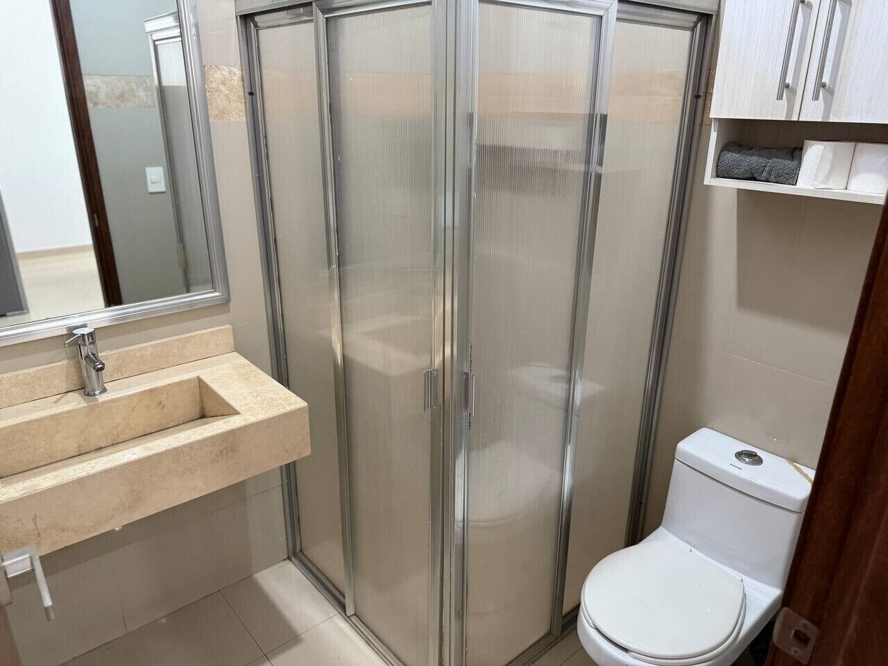 A bathroom with a glass-enclosed shower, a sink, and a toilet.