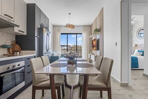 A modern kitchen with a dining area, large windows, and a view of the outdoors. - NOK Modern 2BR at The Towers by Vistacana (Punta Cana)