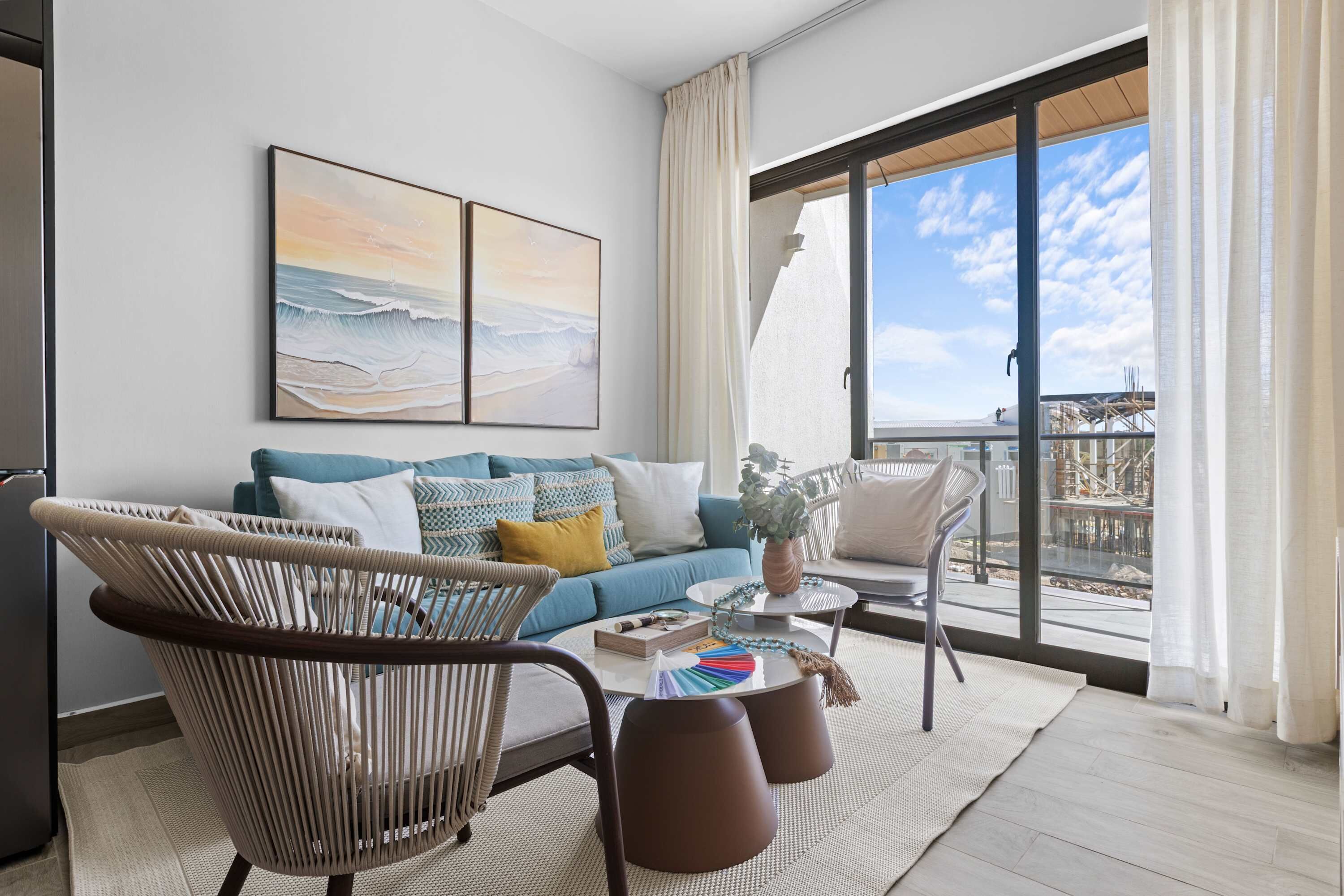 Una sala de estar moderna con un sofá, sillas y un ventanal con vistas al mar.