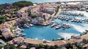 Un puerto deportivo con barcos amarrados, rodeado de edificios residenciales con tejados de tejas rojas.
