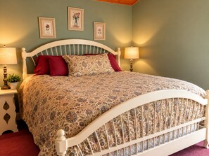 Un lit avec une couvre-lit à motifs, deux oreillers et une tête de lit. Deux lampes murales sont fixées de chaque côté du lit.
