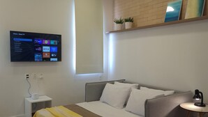 Quarto moderno com cama, mesa de cabeceira, televisão e janela.