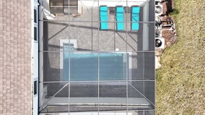 Ein Pool auf dem Dach mit Glasveranda, einer Ziegelwand und einem Rasenbereich.