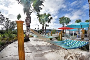 Une zone de plage aménagée avec des hamacs, des parasols et des palmiers.