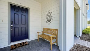 Eine dunkelblaue Tür mit Zahlenschloss, eine Holzbank und ein dekoratives Wandbild.
