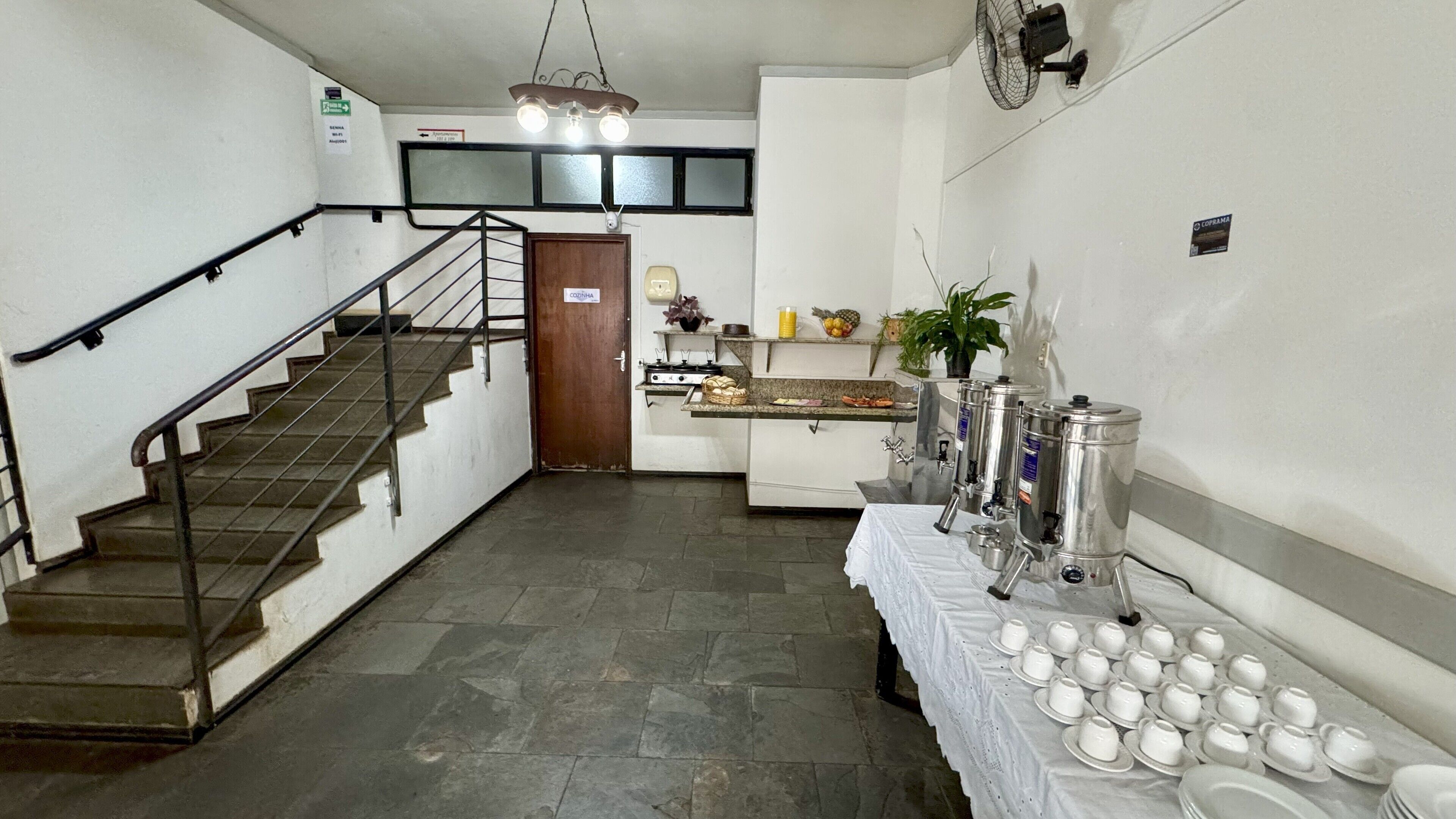 A hotel corridor with a staircase, a kitchenette, and a buffet area with tea service.