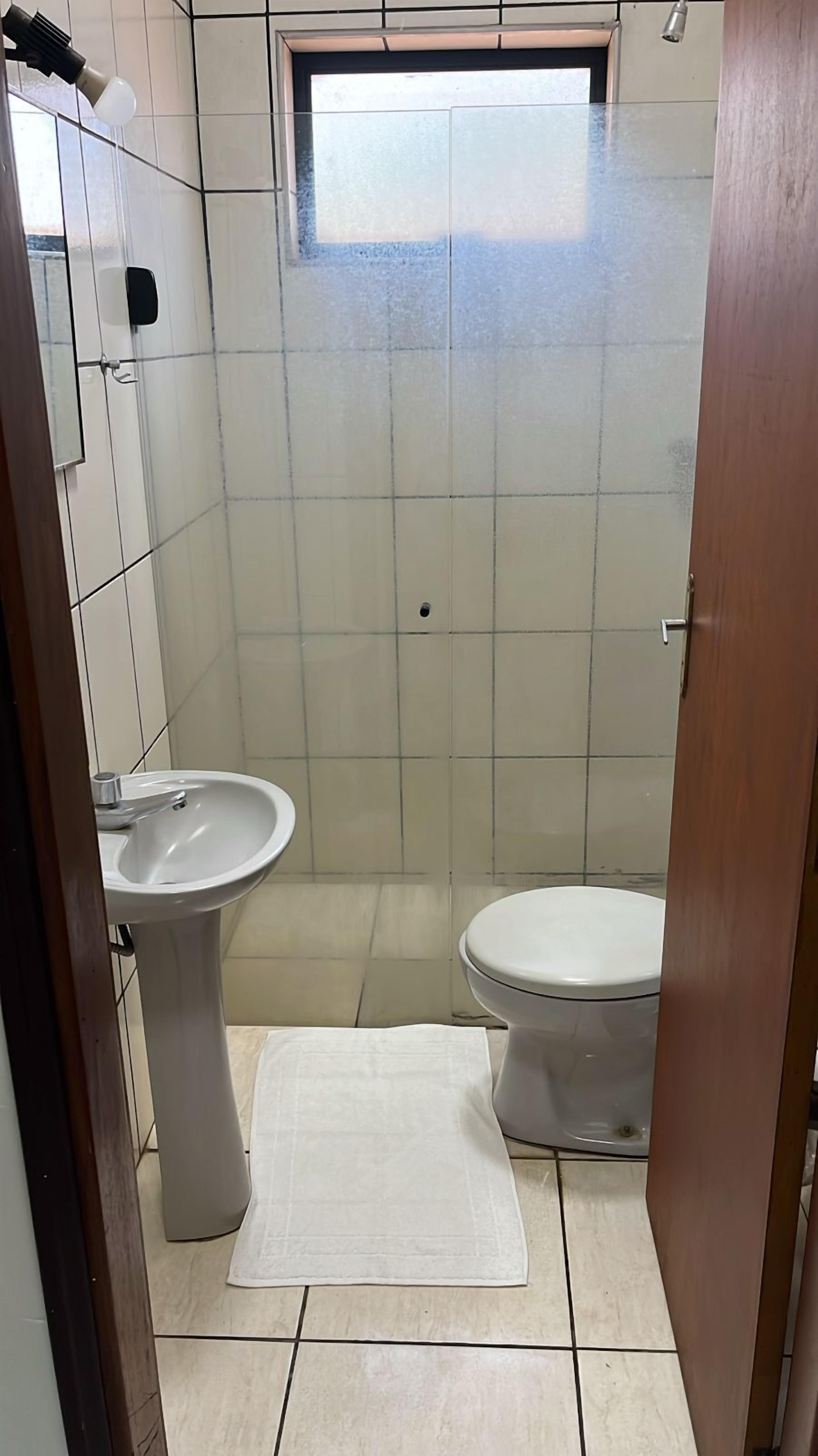 A small bathroom with a white sink, toilet, and a small window.