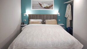 A neatly made bed with a patterned bedspread, two pillows, a wall-mounted clock, and a framed picture above the bed. - Lovely apartment in Kraljevica with WiFi (Kraljevica)