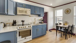 A kitchen with blue cabinets, a white countertop, a stove, and a microwave.