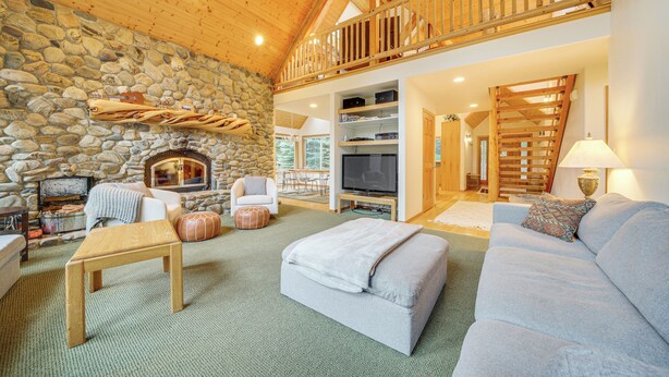 A cozy living room with a stone fireplace, a wooden ceiling, a television, and a comfortable seating area. - 19 Mi to Slopes at Crystal Mtn: Getaway w/ Hot Tub (Enumclaw)