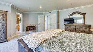 Une chambre à coucher avec un grand lit, une commode, un téléviseur et une cheminée.