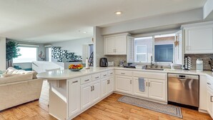 Une cuisine moderne avec des meubles blancs, un lave-vaisselle et un grand îlot central.