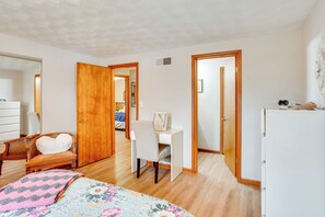 Un dormitorio con cama, escritorio y silla. Se ve un armario y un espejo en la pared.