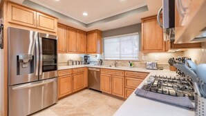 A modern kitchen with wooden cabinets, stainless steel appliances, and a gas stove. - Marbella Lane - Charming 4BR Bungalo for Relaxing Retreat (Fullerton)