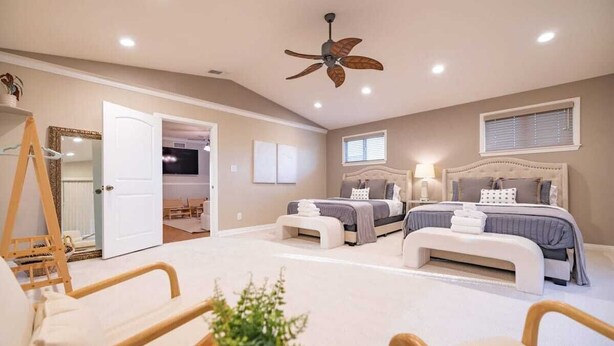 A bedroom with two beds, a ceiling fan, a bedside table, a chair, and a plant. - Marbella Lane - Charming 4BR Bungalo for Relaxing Retreat (Fullerton)