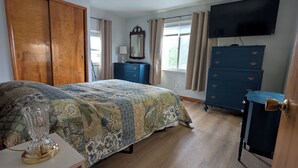 Ein Schlafzimmer mit Bett, Schminktisch, Fernseher und Kleiderschrank.
