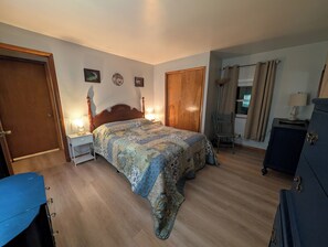 Een slaapkamer met een houten bed, nachtkastjes met lampen, een kledingkast en een stoel.